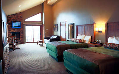 cabin room with two queen size beds, a leather couch, a fireplace, and television set