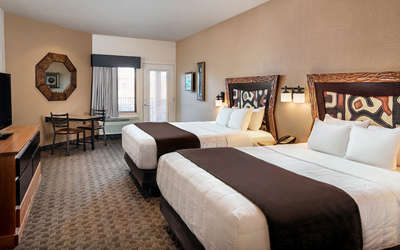 An interior of a Kalahari Resorts hotel room featuring double queen beds and a balcony.