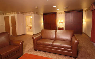 hospitality suite living room with a leather couch and chair and two Murphy beds in the background