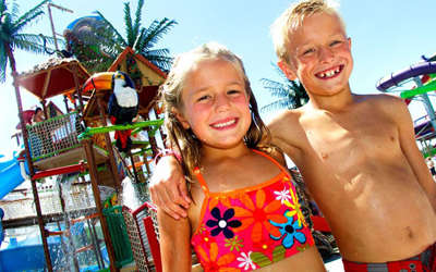 a brother and sister posing for a photo in the outdoor waterpark