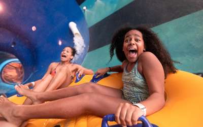 Mom and daughter screaming going down a group toilet bowl waterslide