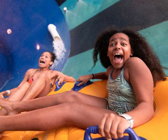 Mom and daughter screaming going down a group toilet bowl waterslide