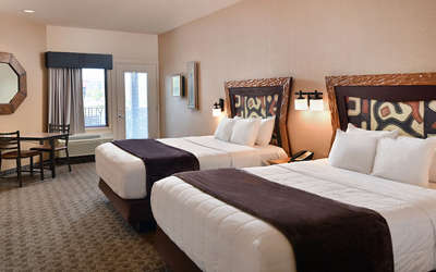 An interior of a Kalahari Resorts hotel room featuring double queen beds and a balcony.