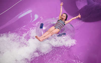 A little girl excited going down water slide.