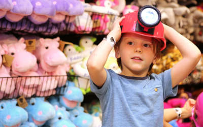 a boy with a hard hat on by a wall filled with stuffed animals