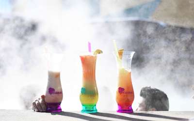 3 Monster Cocktail Drinks sitting on the side of a steaming outdoor whirlpool