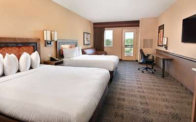 an overview of inside the Two Bedroom Suite. Consists of beds, desk, microwave, and tv.