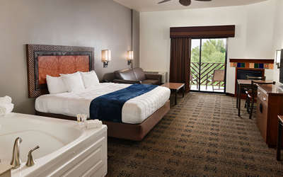 An interior of a Kalahari Resorts hotel room named the King Whirlpool featuring a king bed and balcony, and hot tub.