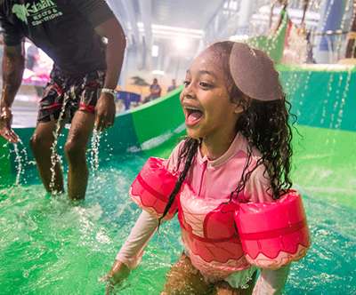 A little girl laughs as she splashes in a water play area