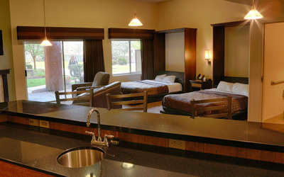 Overview of the Hospitality Suite. Consists of a kitchen area, fireplace, tv, two beds, and living area